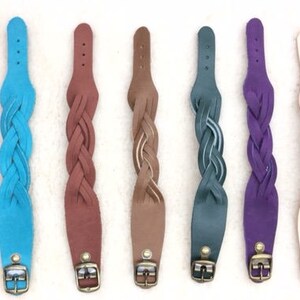 May include: Ten braided leather bracelets in various colors, including gray, blue, brown, teal, purple, and pink. Each bracelet has a silver buckle.
