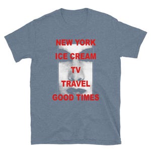 May include: A blue short-sleeve t-shirt with the words "NEW YORK ICE CREAM TV TRAVEL GOOD TIMES" in red. A black and white image of a face is in the center of the shirt.