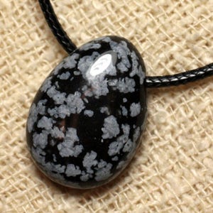 May include: Black and white snowflake obsidian pendant on a black cord. The pendant is a smooth, oval shape with a speckled pattern.