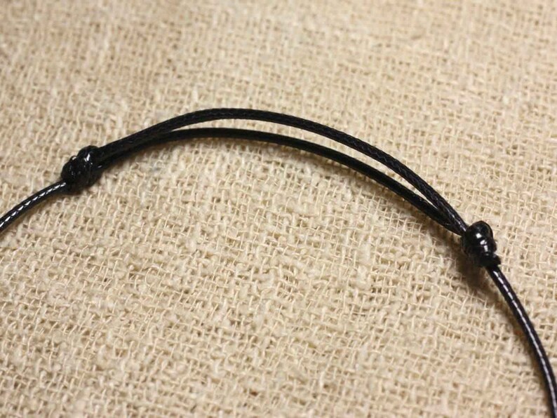 May include: A black cord necklace with a simple knot closure.