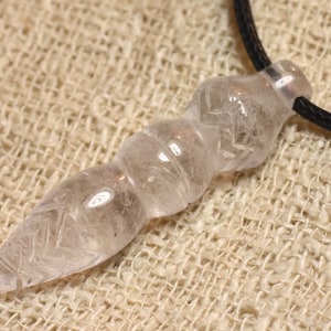 Peut inclure: Un pendentif en cristal de quartz clair avec un design facetté et pointu. Le pendentif est attaché à un cordon noir.