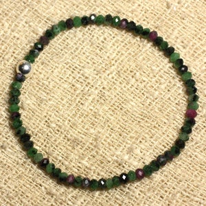 Peut inclure: Un bracelet en pierres précieuses vertes et roses avec un fermoir en argent. Le bracelet est composé de petites perles facettées et est enfilé sur un cordon élastique fin et transparent.