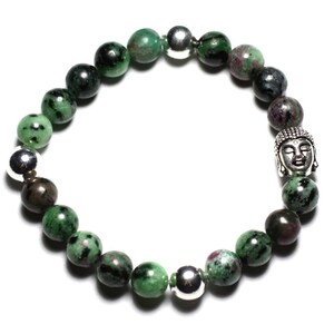Peut inclure: Un bracelet vert et argent avec un charme Bouddha. Le bracelet est fait de pierres vertes et noires avec des perles argentées.