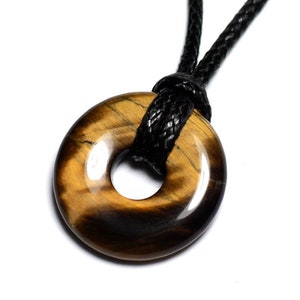Può includere: Un ciondolo in pietra di occhio di tigre marrone e oro a forma di anello, appeso a un cordoncino intrecciato nero.