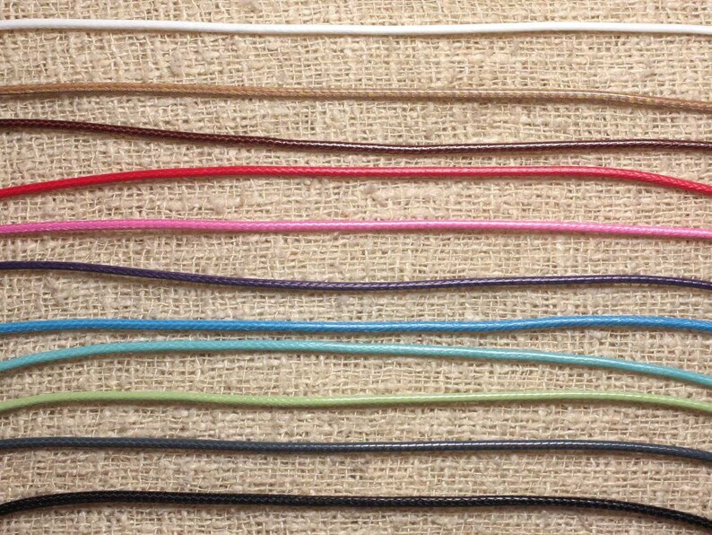 May include: A variety of colors of waxed cord, including white, brown, red, pink, purple, blue, green, gray, and black, are displayed on a burlap background.