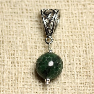 Peut inclure: Un pendentif en pierre précieuse verte avec une bélière en filigrane argentée. La pierre précieuse est ronde et de couleur vert foncé avec des veines vert clair.