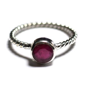 Peut inclure: Une bague en argent avec une bande torsadée et une pierre précieuse ronde rouge foncé.