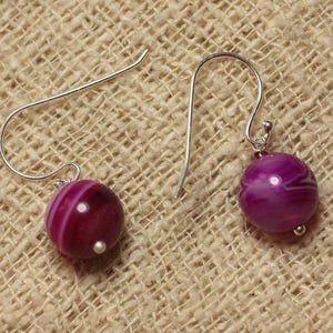 Può includere: Un paio di orecchini d'argento con perline di agata rosa e bianca. Gli orecchini hanno un design semplice con un piccolo anello nella parte superiore per fissarli all'orecchio.