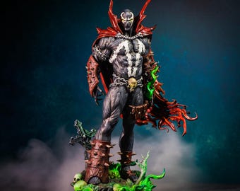Könnte beinhalten: Detaillierte Figur der Comicfigur Spawn. Die Figur ist überwiegend schwarz und grau, mit rotem Umhang und Akzenten. Sie steht auf einem Sockel mit Totenköpfen und einem Kreuz, mit grünen und roten Akzenten.