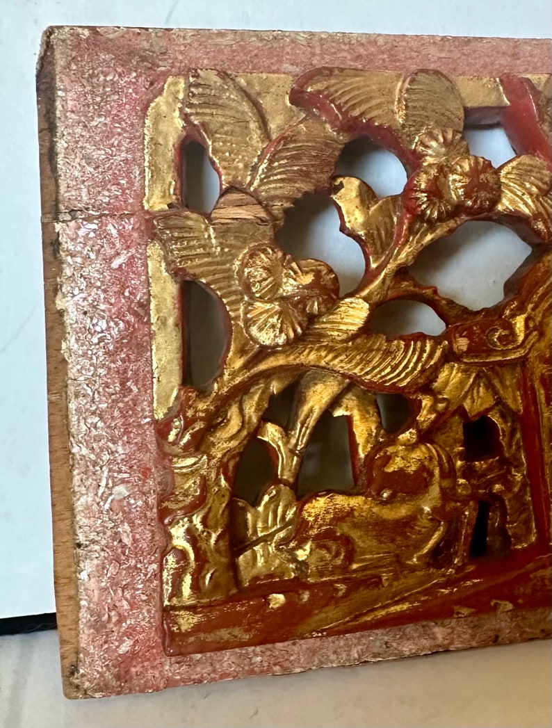 May include: A carved wooden panel with intricate floral and bird designs. The panel is painted in shades of red and gold, with the gold paint showing signs of wear and tear. The panel is likely from a traditional Chinese or Asian home.