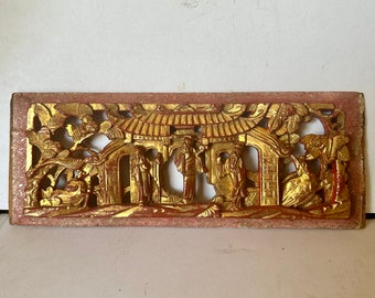 May include: A rectangular wooden panel with intricate carvings depicting a Chinese garden scene. The panel is painted in shades of red and gold, with figures and foliage details.