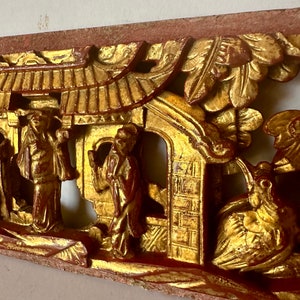 May include: A carved wooden panel with a gold and red finish. The panel depicts a scene with figures, a building, and a bird. The panel is a traditional Chinese art form.