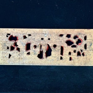 May include: A wooden panel with intricate cutouts painted in red. The panel has a rustic, aged appearance and is perfect for adding a touch of traditional style to a home decor project.