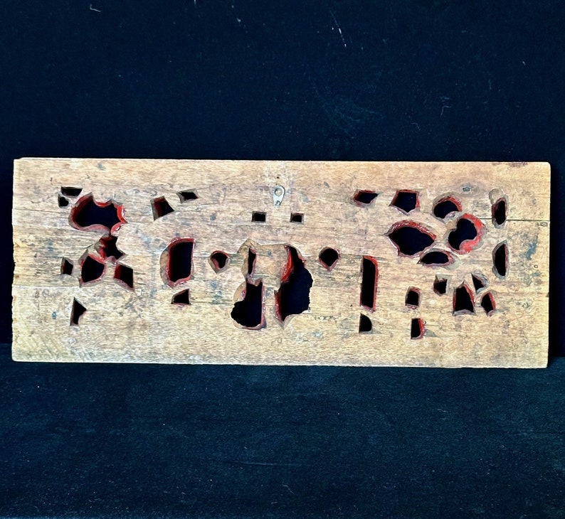 May include: A wooden panel with intricate cutouts painted in red. The panel has a rustic, aged appearance and is perfect for adding a touch of traditional style to a home decor project.