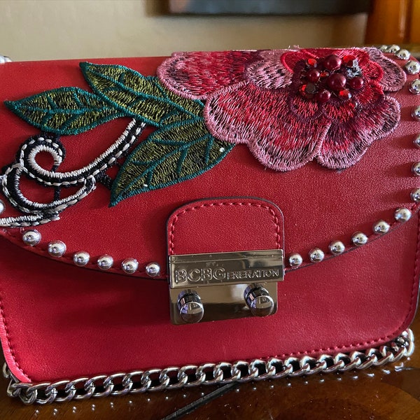 BCBG  Millie red Vegan cross body bag. Silver studs, rise  appliqué. Silver chain perfect for a night out on the town.