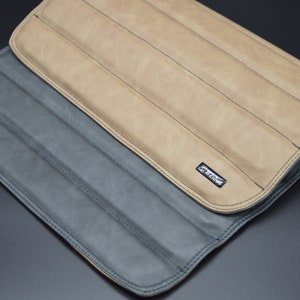 May include: A brown leather roll-up case with a gray leather lining. The case has multiple slots for holding items like pens, pencils, or tools. The case has a small black label with the word "CRAFTED" printed on it.
