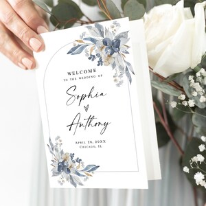 Puede incluir: Un cartel de bienvenida de boda blanco con un diseño floral azul y dorado. El cartel dice "Bienvenido a la boda de Sophia & Anthony, 24 de abril de 20XX, Chicago, IL."