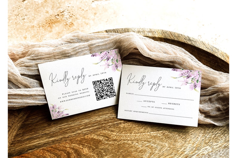 May include: Two white RSVP cards with a floral design and the text "Kindly reply by April 10th". One card has a QR code and the text "Please scan to RSVP or our wedding website: www.ourweddingday.com". The other card has a section for the guest's name, accepts, regrets, number of guests attending, and dietary requirements.