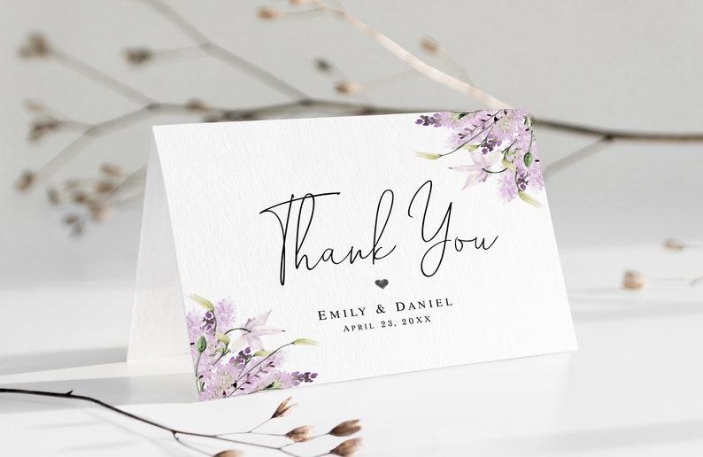 May include: A white thank you card with a purple floral design and the text "Thank You" in black script. Below the text is "Emily & Daniel" and "April 23, 20XX" in black.