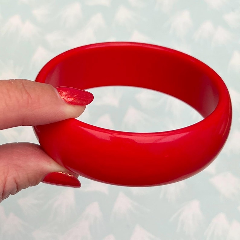 Pu&ograve; includere: Un braccialetto rosso acceso. La superficie liscia e lucida riflette la luce, evidenziando il colore audace. Questo braccialetto rotondo e solido &egrave; un accessorio classico, perfetto per aggiungere un tocco di colore.