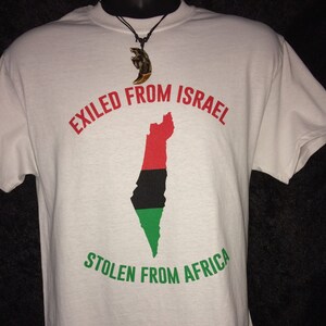 May include: White t-shirt with the text "EXILED FROM ISRAEL" in red and "STOLEN FROM AFRICA" in green. A map of Israel is printed in red, black, and green. A necklace with a brown pendant is also visible.