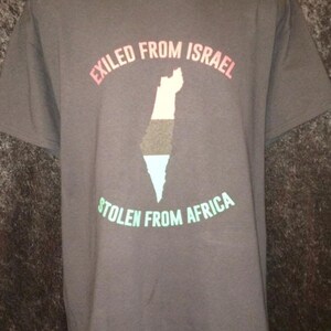May include: Dark gray t-shirt with the text "EXILED FROM ISRAEL" in pink and "STOLEN FROM AFRICA" in green. A map of a country is in the center, with colors of black, white, and blue. The shirt has a blue and silver trim at the bottom.
