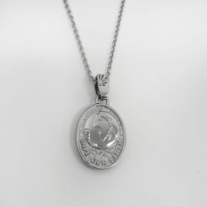May include: Silver necklace with a pendant featuring a textured oval with an image of the Earth and the words "Save Our Earth".