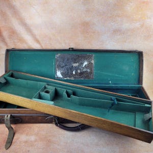 May include: A rectangular wooden case with a hinged lid, featuring a dark brown exterior and a vibrant green felt-lined interior. The interior contains moulded compartments for storage, and the lid displays a rectangular, weathered label.