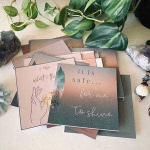 May include: A stack of affirmation cards with a green, pink, and white watercolor background. The top card reads "it is safe... for me to shine".