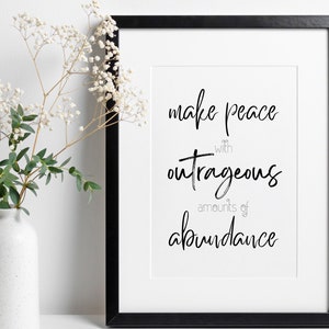 以下が含まれることがあります： 「make peace with outrageous amounts of abundance」というテキストが書かれた白黒の額装されたプリント。