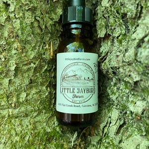 May include: A brown glass bottle with a dropper top and a white label. The label says "littlejaybirdfarm.com", "Naturally Sustainable - Rooted in Tradition", "LITTLE JAYBIRD Farm", "Est. 2014", and "400 Flat Creek Road, Fairview, NC 28730".