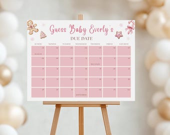 May include: A pink and white "Guess Baby Everly's Due Date" calendar displayed on a wooden easel. The calendar features a grid for tracking dates, with decorative gingerbread and candy cane accents. Balloons in gold and white are in the background.