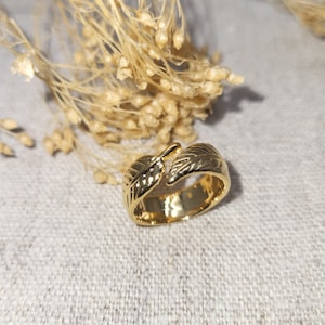 Peut inclure: Une bague ajustable dorée ornée d'un motif de feuille. La bague est en métal et a un style simple et élégant.