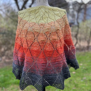 May include: A crocheted shawl with a gradient of yellow, orange, red, and black. The shawl is displayed on a mannequin.