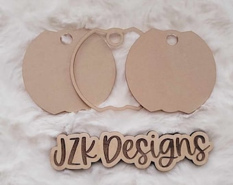 Puede incluir: Dos círculos de madera sin terminar con agujeros para colgar, y un letrero de madera separado que dice "JZK Designs".