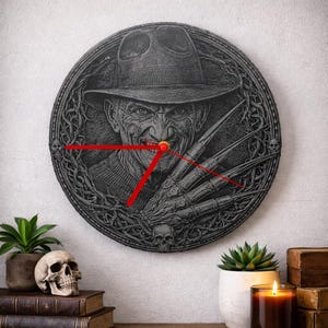 May include: A round, dark gray wall clock featuring a detailed image of a horror movie character with a hat and clawed glove. The clock has red hands and a black border with skull and vine details. A unique piece for a fan.