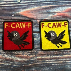 May include: Two square patches with a crow design and the text "F-CAW-F". One patch has a red background, the other is yellow. The crow is black with a gray head and white eye.