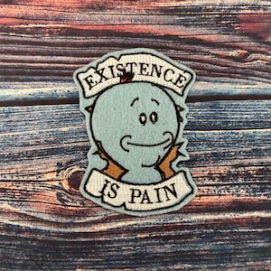 May include: A blue and white embroidered patch featuring a cartoon character and the text "Existence is Pain".