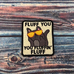 May include: A black cat wearing yellow sunglasses with the text "Fluff You You Fluffin' Fluff" on a white background.