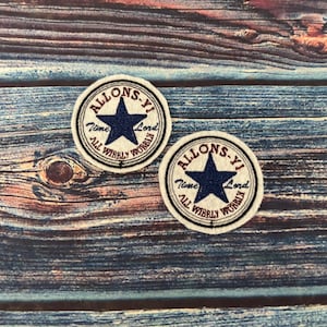 May include: Two white fabric patches with a blue star and red text that reads "Allons-Y Time Lord All Wirely Worbly".