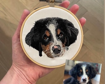 May include: Embroidered portrait of a Bernese Mountain Dog in a wooden embroidery hoop. The dog has black, white, and brown fur. A photo of the dog is shown below the hoop.