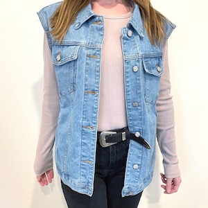 May include: A light blue denim vest with a classic collar, button closure, and two front pockets. The vest is unlined and has a relaxed fit.