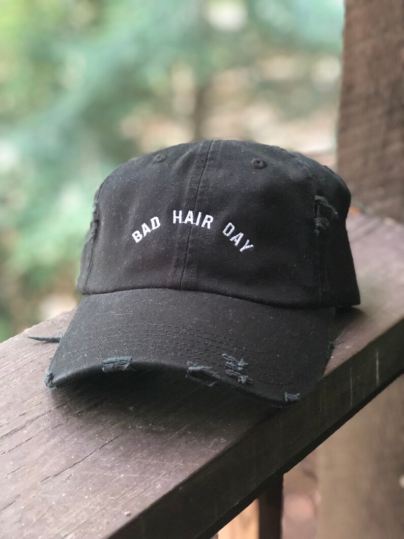 Pode incluir: Bon&eacute; de beisebol preto desgastado com texto bordado branco que diz "Bad Hair Day".