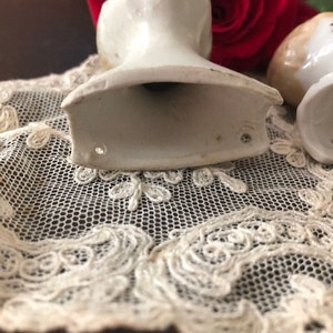 May include: Two vintage porcelain doll heads, one with a white finish and the other with a cream finish. Both heads are missing their bodies and have a hollow base.