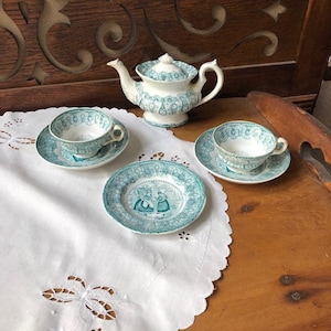 May include: A vintage tea set with a teapot and two teacups and saucers. The set is decorated with a green and white floral pattern. The teacups and saucers have a scalloped edge.