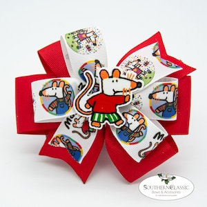 May include: A red and white hair bow featuring a cartoon mouse character. The bow has a layered design with red and white ribbons. The white ribbons display the mouse character in a circular design. A mouse character is also attached to the center of the bow.