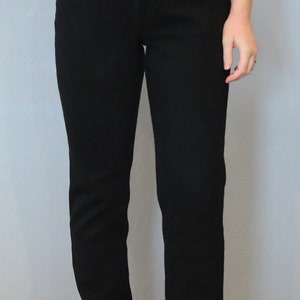 Puede incluir: Vaqueros negros de mezclilla con corte recto cl&aacute;sico. Los vaqueros tienen cierre de bot&oacute;n y cremallera, bolsillos delanteros y traseros, y un peque&ntilde;o detalle de logotipo en el bolsillo delantero. El modelo lleva una camiseta blanca.