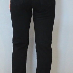 Puede incluir: Vaqueros negros de mezclilla con corte recto. La parte trasera tiene dos bolsillos y un parche con el logo de Tommy Hilfiger. Los vaqueros se llevan con sandalias de cu&ntilde;a negras. La modelo lleva un top blanco.