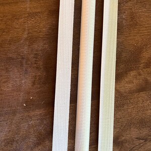 May include: Three wooden dowels, two are flat and one is round. The dowels are all the same length and are made of light wood.