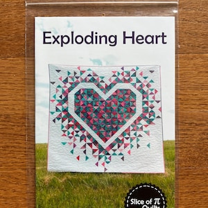 May include: A quilt pattern titled "Exploding Heart" featuring a heart design made of colorful triangles. The pattern is packaged in a clear plastic sleeve. The design includes pink, teal, and white colors. The brand name "Slice of Pi Quilts" is also visible.